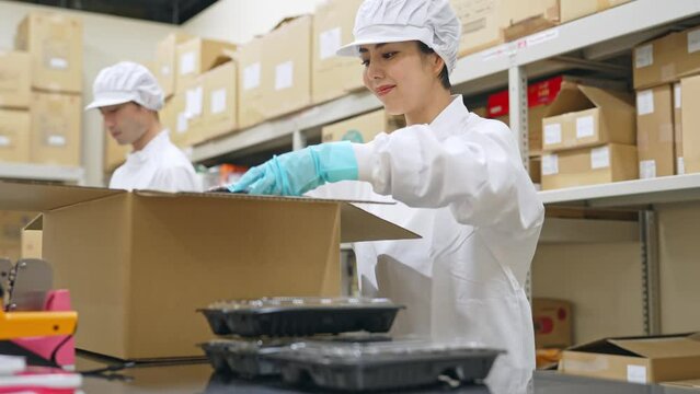 食品を箱詰めする女性　給食センター　宅配食　包装工場