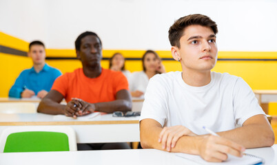 Fototapeta premium Young man sitting at desk in classroom of school for taxi drivers.