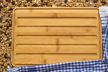 Empty cutting board surrounded with granola chocolate nut crumble with space for text. Granola background