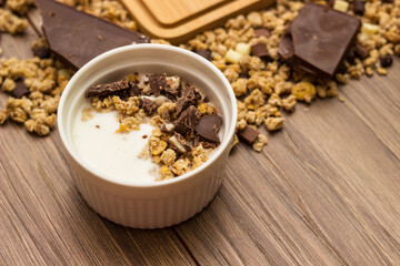Granola in a bowl surrounded by granola on table. Granola background