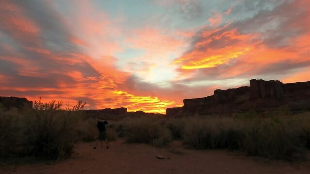 A photographer capturing a photo of a spectacular sunrise over the cliffs of Canyonlands National Park in Utah.