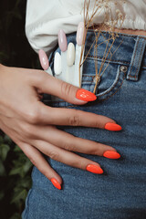 Bright neon manicure on female hands on the background of jeans. Nail design.