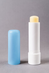 Chapstick open tube over gray background. Moisturizing lip balm for dry lips macro. Colorless protective lipstick for winter cosmetic concept. Toiletries for children, men and women.