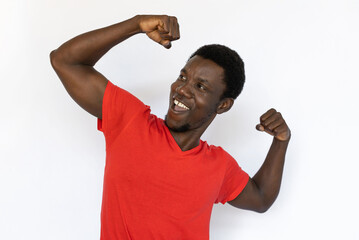 Portrait of excited African American man showing biceps. Happy young male model with short dark...