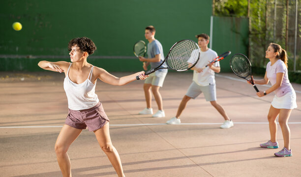 Sportive woman in shorts and t-shirt playing frontenis on outdoors court