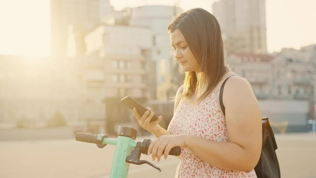 A girl rents an electric scooter with an application on her phone.