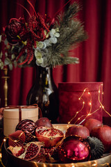 
Red velvet still life. A beautiful arrangement of items with fir branches in a bouquet, a gift box with a crane on a tray and a garland. Beautiful red screensaver for your phone