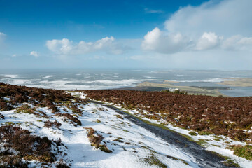 Small walking path covered with snow. Ocean and blue sky in the background. County Sligo. Winter season in Ireland. Stunning Irish landscape scene.