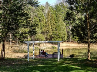 loving couple sitting in pergola swing overlooking small pond surrounded by trees