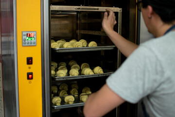 Baker places the croissants inside the oven.