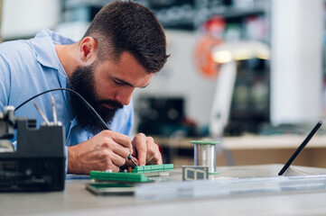 Electronics engineer working in a workshop with tin soldering parts