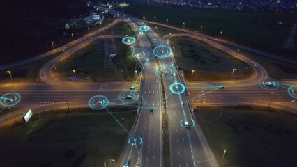 Self-driving autonomous cars move along a suburban traffic intersection in the evening. Neon HUD...