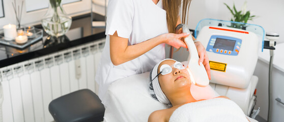 Non-surgical options of aesthetic medicine. Wide indoor shot advertising thermolifting - procedure that helps tighten skin, reducing wrinkles, and improve tone and complexion. Young Asian woman lying