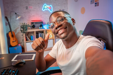Young cheerful streamer man smiling confident make selfie by smartphone at gaming room while...