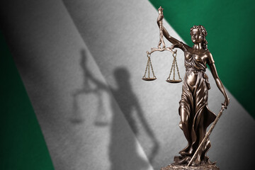 Nigeria flag with statue of lady justice and judicial scales in dark room. Concept of judgement and...