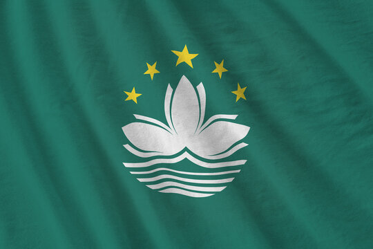 Macau flag with big folds waving close up under the studio light indoors. The official symbols and colors in banner - Powered by Adobe