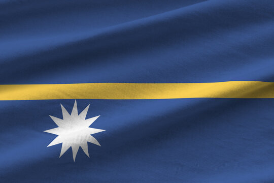 Nauru flag with big folds waving close up under the studio light indoors. The official symbols and colors in banner
