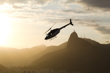 Fototapeta na wymiar Helicopter at sunset with Christ the Redeemer in Rio de Janeiro in the background