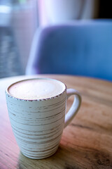 A frothy cappuccino cup on a wooden table in a cafe as a morning ritual