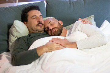 Homosexual men sleeping in bed in morning. Bearded handsome gays in pajamas lying with closed eyes, hugging, holding hands, resting on weekend together. LGBT, love, sleep cycle concept