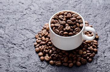 Roasted coffee beans in a cup, on dark background, close-up image, space for text