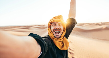 Happy male tourist taking selfie on sand dunes in the Africa desert, Sahara National Park -...