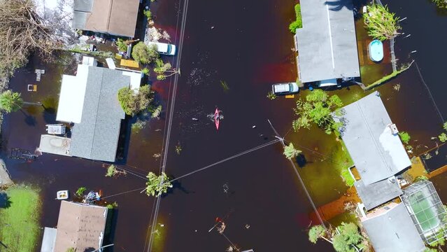 Kayak boat floating on flooded street surrounded by hurricane Ian rainfall flood waters homes in Florida residential area. Consequences of natural disaster