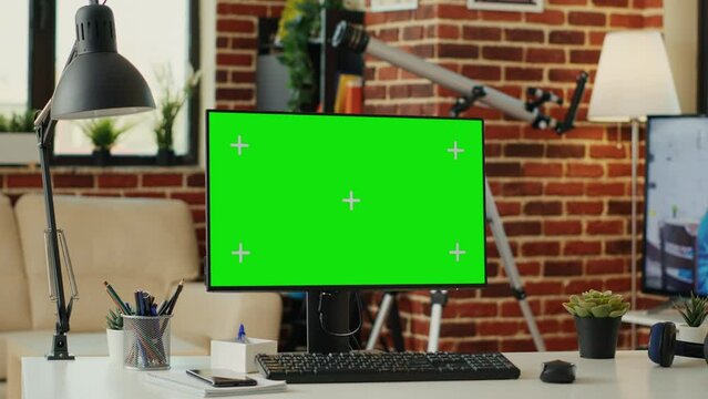 Greenscreen display on computer with empty desk in living room, workspace with chroma key blank background. Showing isolated copyspace with mokcup template on desktop monitor at home.