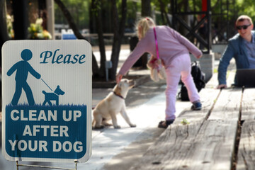 Obraz premium Girl with a dog outside. The warning sign: Clean up after your dog.
