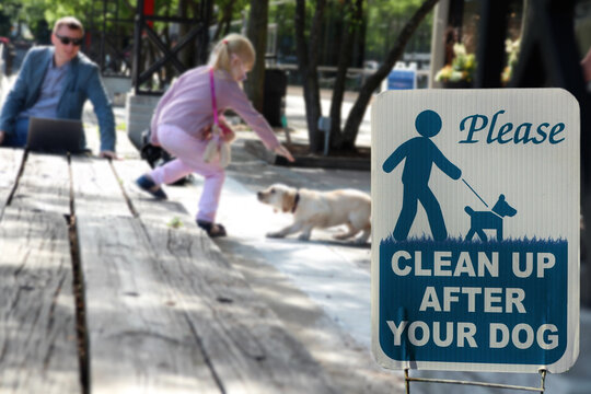 Girl with a dog outside. The warning sign: Clean up after your dog.