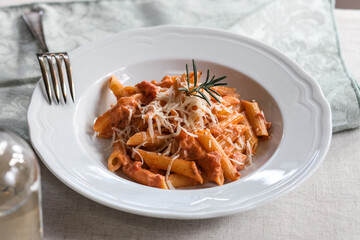 penne alla vodka pasta sauce with rosemary in white bowl