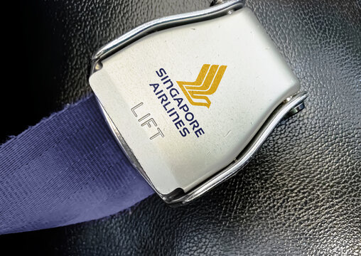 detail of the buckle of the seat belt with the logo of Singapore Airlines on an empty seat