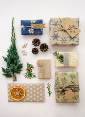 Eco friendly Christmas composition with gift boxes in craft reusable paper and natural decor on white background top view. Zero waste environmentally friendly Christmas concept.