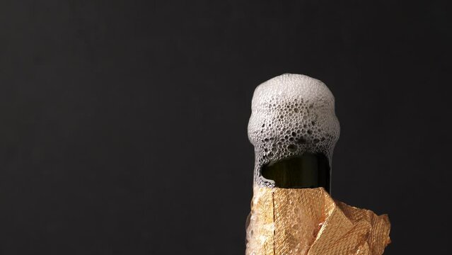 Opening champagne bottle with splashing on black background. New Year celebration