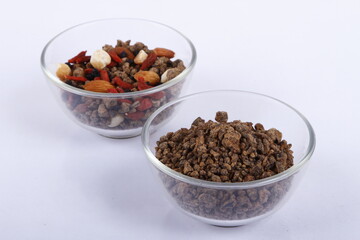 Bowls of assorted nuts and muscovado rocks against a white background