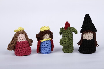 Crocheted king, queen, dragon and witch finger puppets on a white background