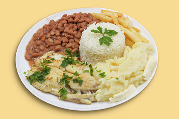 Brazilian meal with rice, beans and mashed potatoes on yellow background
