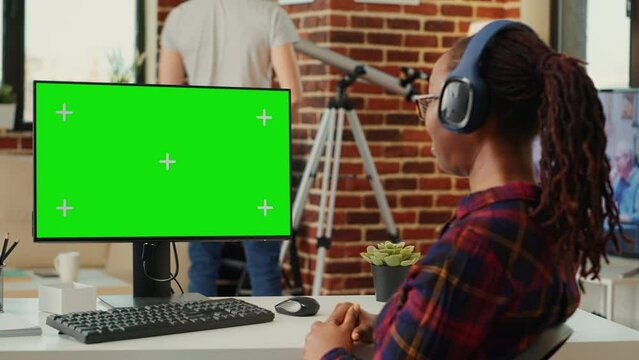 Female manager analyzing greenscreen template on monitor, working with isolated mock up background at desk. Using blank chroma key display with copy space on personal computer at home.