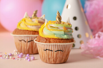 Cute sweet unicorn cupcakes on beige table
