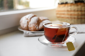 Tea bag in glass cup on white windowsill. Space for text