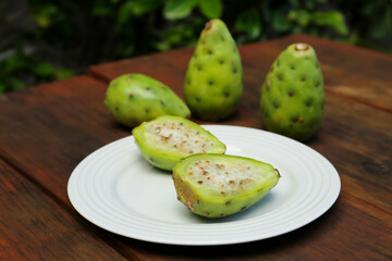 Tasty prickly pear fruits on wooden table outdoors