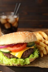 Delicious burger, soda drink and french fries served on wooden table, closeup