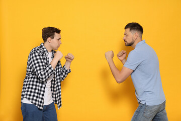 Two emotional men fighting on yellow background