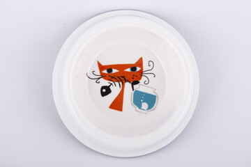 Top shot of a white plate with a cartoon cat eating a fish design