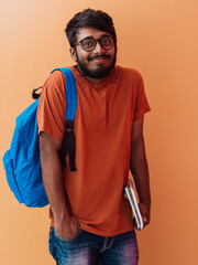  Indian student with blue backpack, glasses and notebook posing on orange background. The concept of education and schooling. Time to go back to school