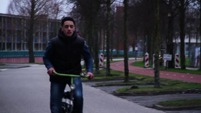 Young middle eastern man cycling through a city in the Netherlands