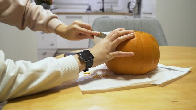 slider shot of a woman carving orange pumpkin at home for the Halloween
