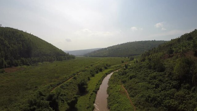 Aerial over muddy river in remote jungle mountains of Rwanda, Africa
