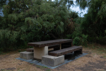 A place for tourists to relax and have a picnic. Benches table around trees without people.