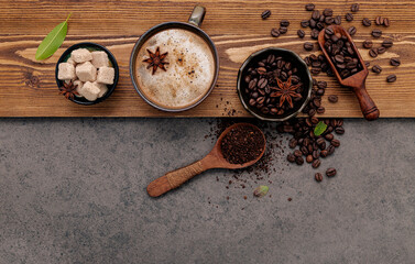 Roasted coffee beans with coffee cup setup on dark stone background.